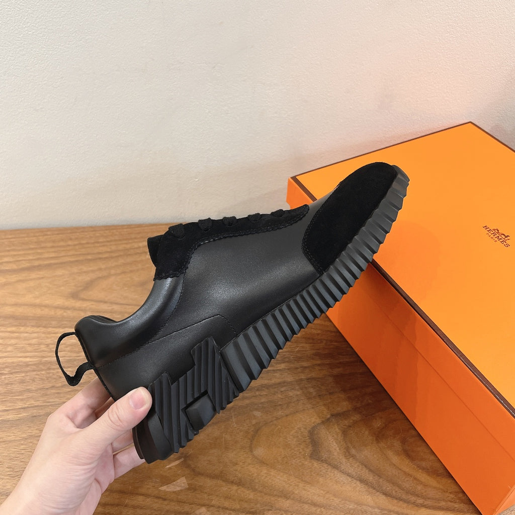 Unisex sneakers side view, black upper with ribbed rubber sole and pull tab