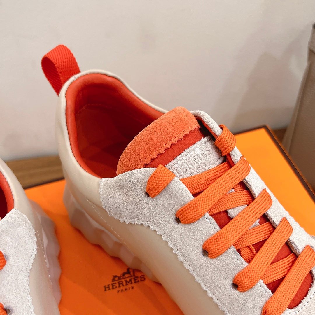 White sneaker upper with orange laces, orange strap detail, and red interior lining.
