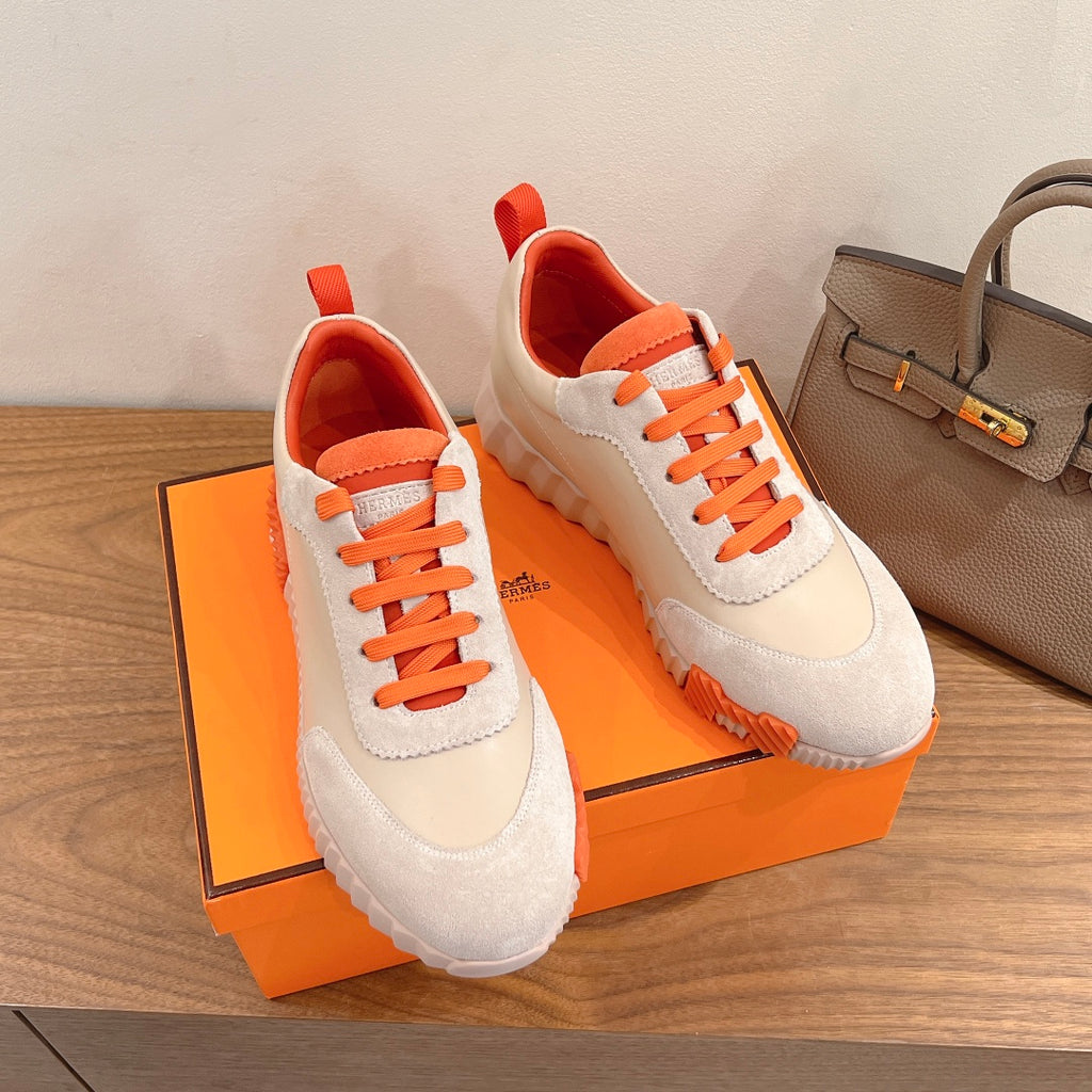White and orange lace-up sneakers with suede-like panels and cushioned tongue.