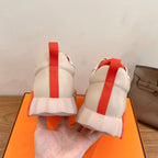 Rear view of white sneakers with orange heel tab strap and cushioned back collar.