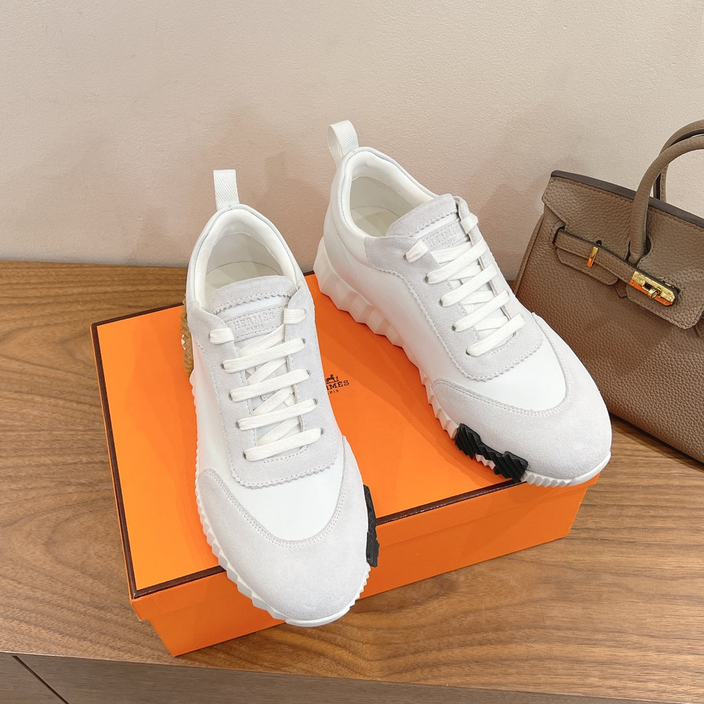 White lace-up sneakers with padded tongue, thick sole, and contrasting dark tread tips
