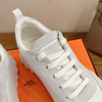 Close-up of white lace-up sneaker with Hermes logo on the side panel