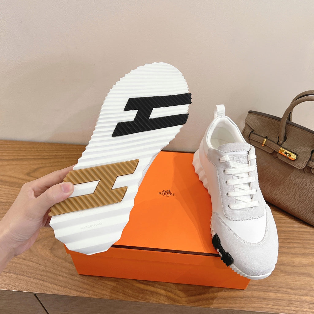 Shoe outsole view of white sneakers with textured tread and bold logo
