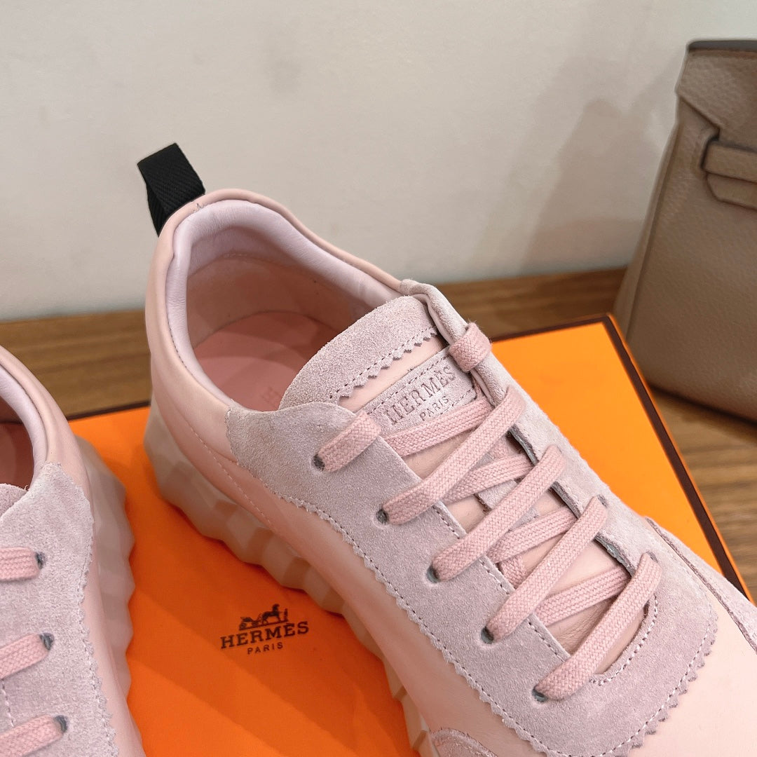 Hermes pink sneaker with lace-up closure, suede paneling, and logo on tongue