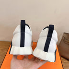 Pair of white Hermes sneakers showing rear heel tabs and navy elastic accents.