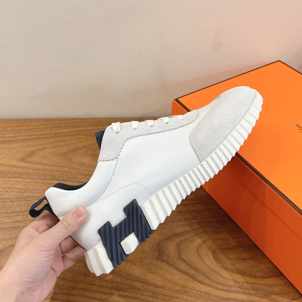 White slip-on style sneakers with navy logo, ridged sole, and side paneling.