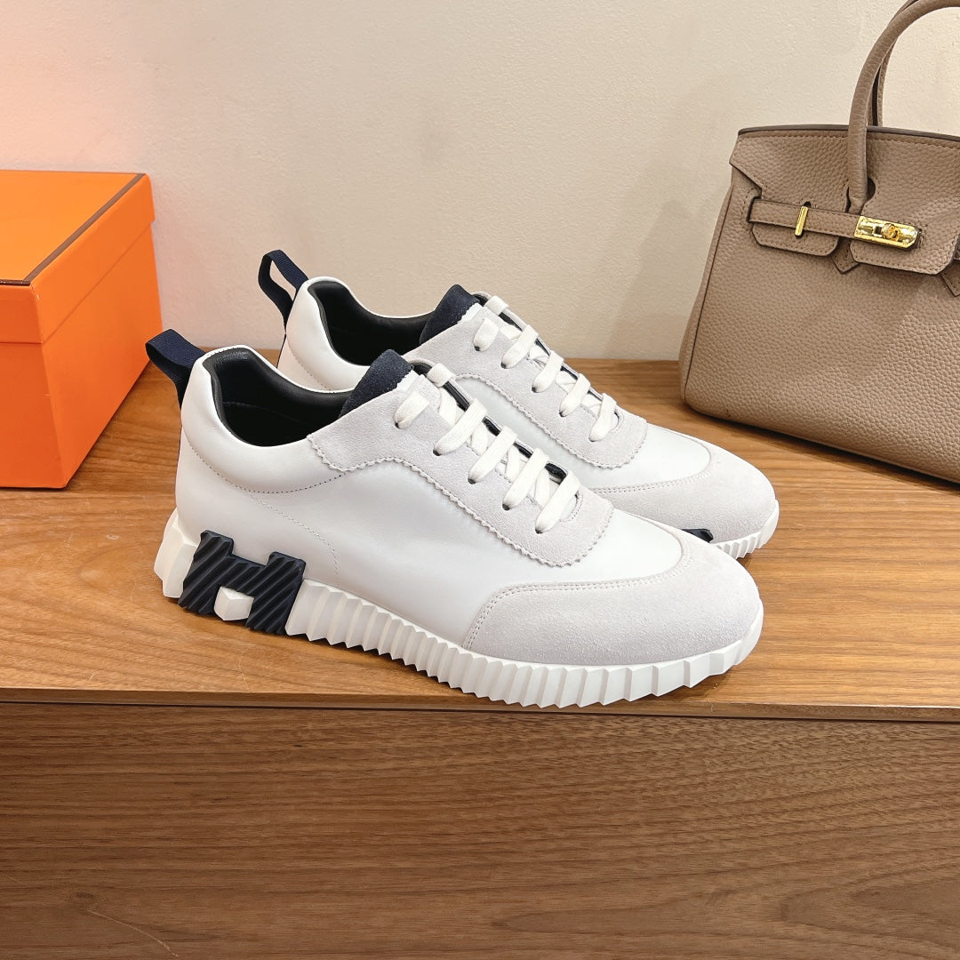White Hermes sneakers with navy logo stripe, cushioned sole, and lace-up closure.
