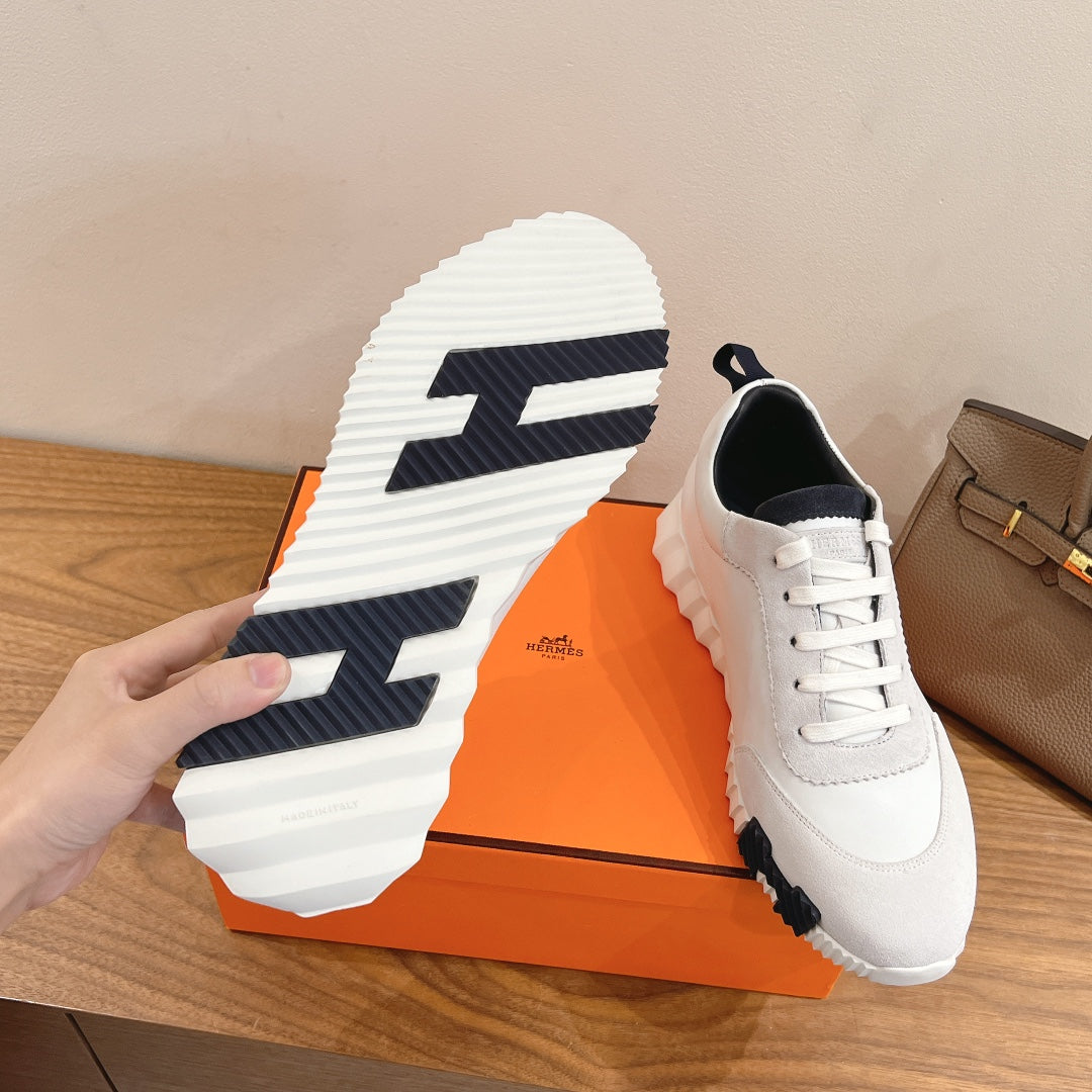 White sneaker outsole with navy pattern and lace-up Hermes upper.