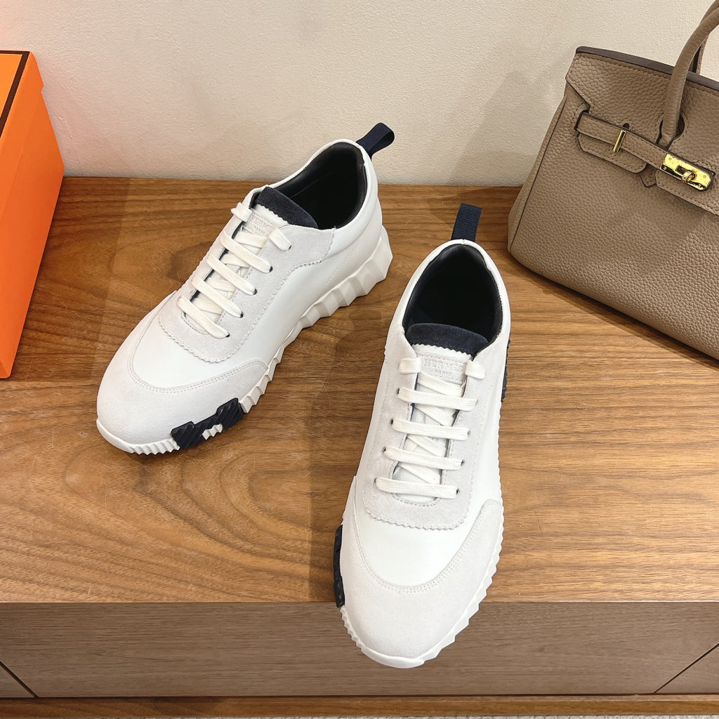 White lace-up Hermes sneakers with navy heel lining and textured rubber sole.