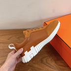 Tan sneakers with lace-up upper and thick white ridged sole, held up
