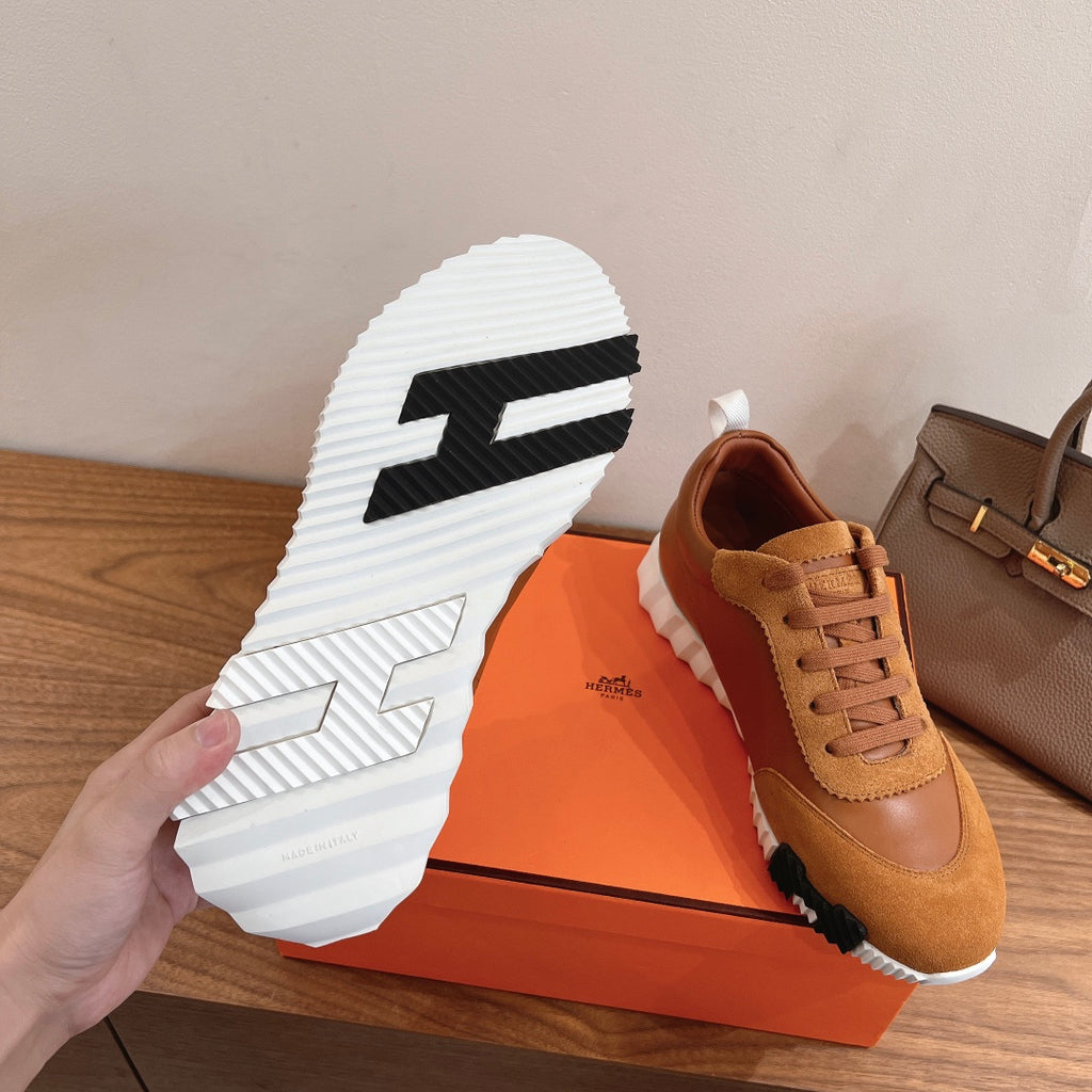 White tread outsole with black pattern on tan sneaker, laid on box
