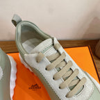 Detail of pale green and off-white sneaker with lace panel and Hermes Paris logo on side