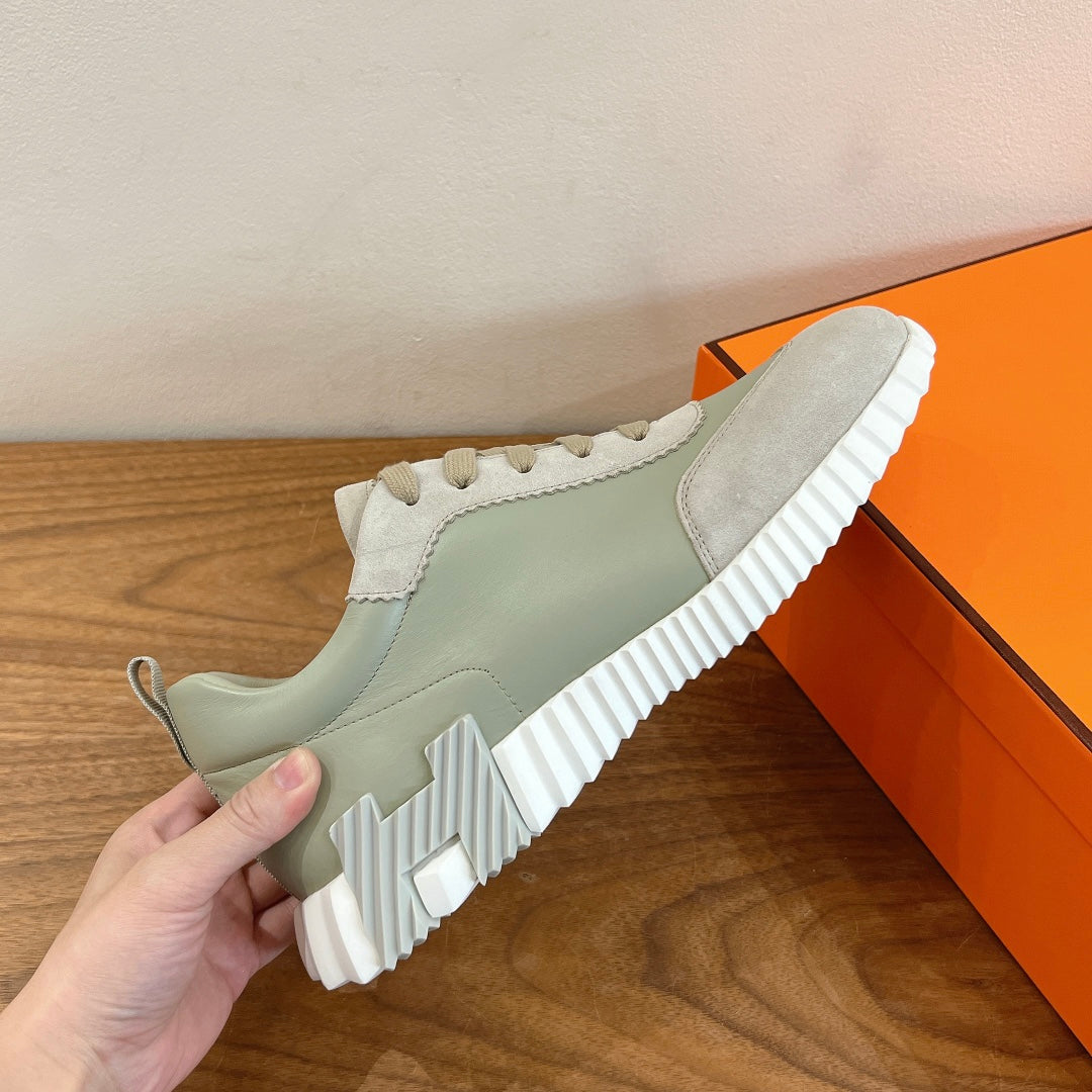 Side view of pale green and off-white sneakers with lace-up top and thick white tread sole