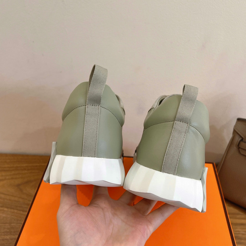 Back view of pale green sneakers with elastic-like pull tab and white ridged heel sole