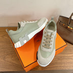 Unisex sneakers in pale green and off-white on box, featuring lace-up design and chunky sole