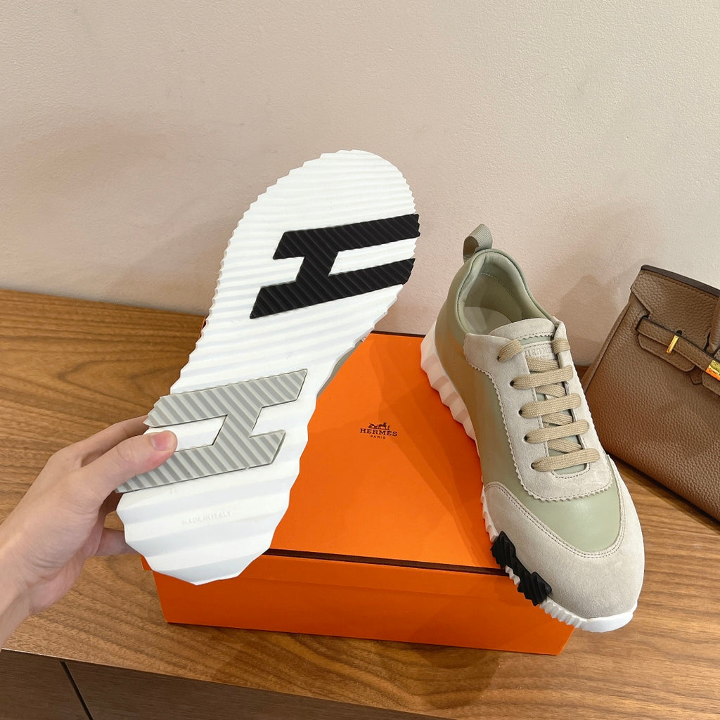 Sneaker outsole view with white rubber tread and black logo on pale green/white upper