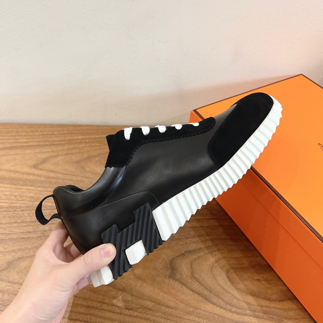 Side view of black sneakers with white ridged outsole and contrast lace-up panel