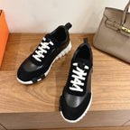 Black low-top sneakers with white lace-up detail and grippy white sole