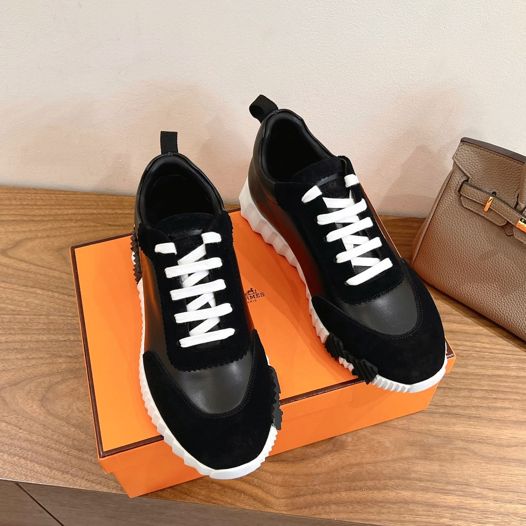 Pair of black sneakers with white laces, padded tongues, and thick white outsole
