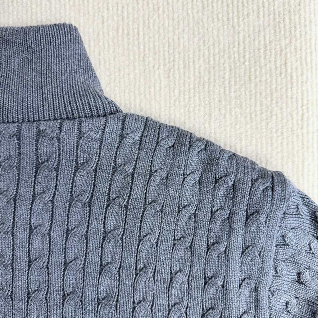 Cable-knit sleeve on a blue puffer jacket with ribbed cuff and knit texture