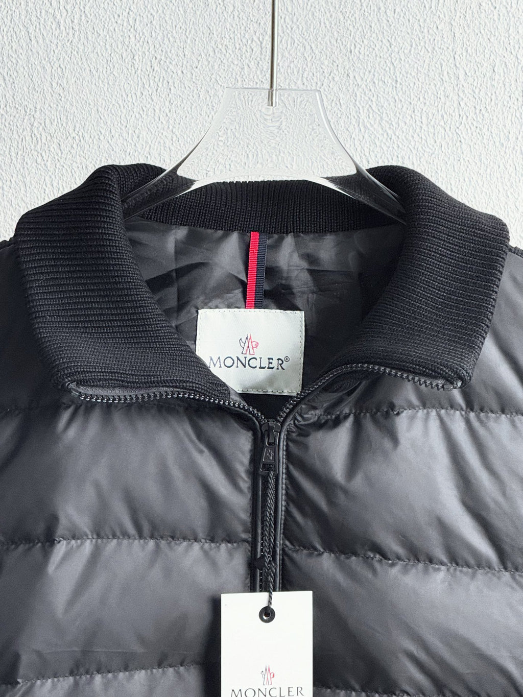 Dark quilted puffer jacket close-up with zip, knit cuffs, and logo label