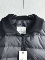 Dark quilted puffer jacket close-up with zip, knit cuffs, and logo label