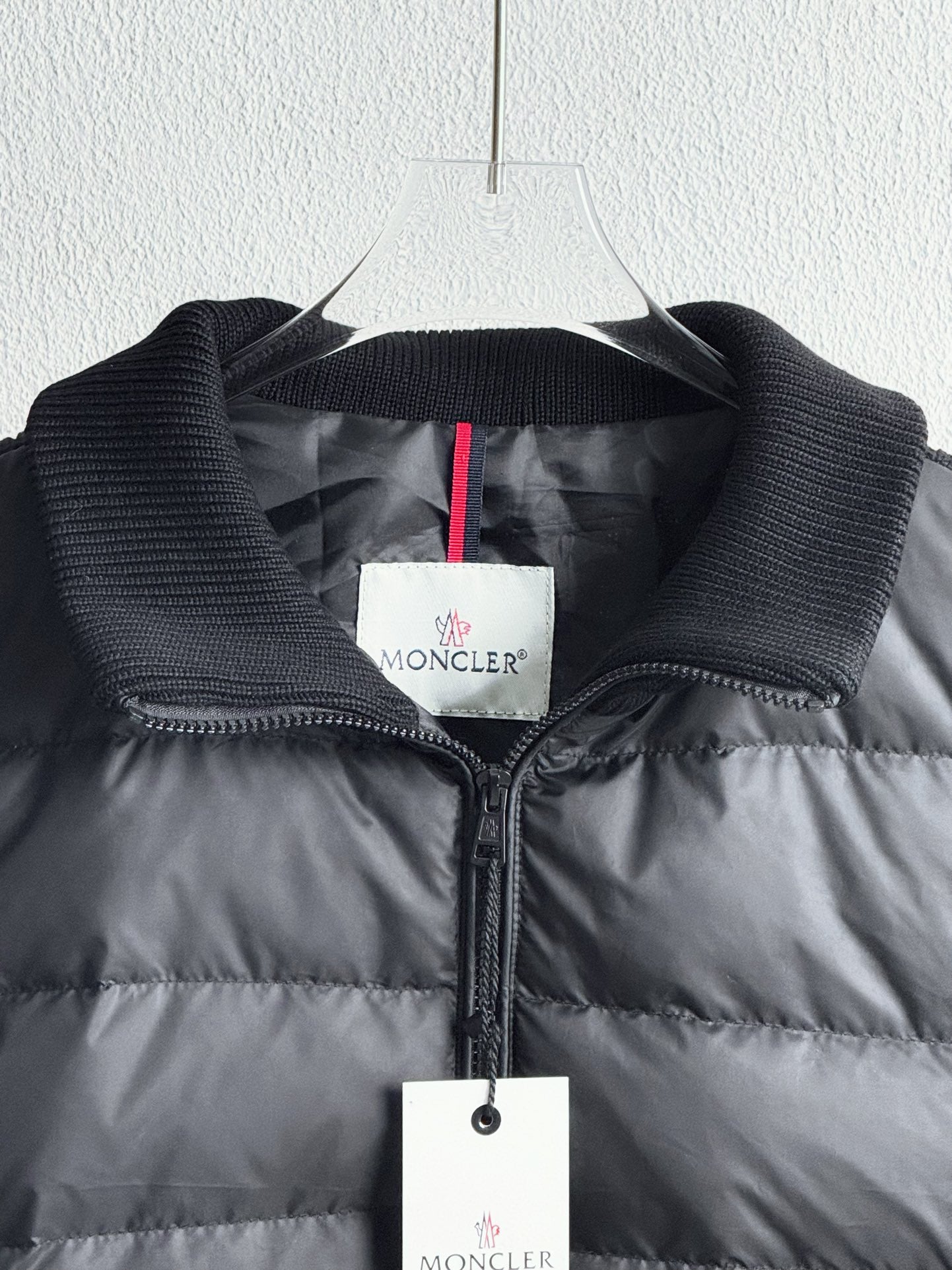 Dark quilted puffer jacket close-up with zip, knit cuffs, and logo label