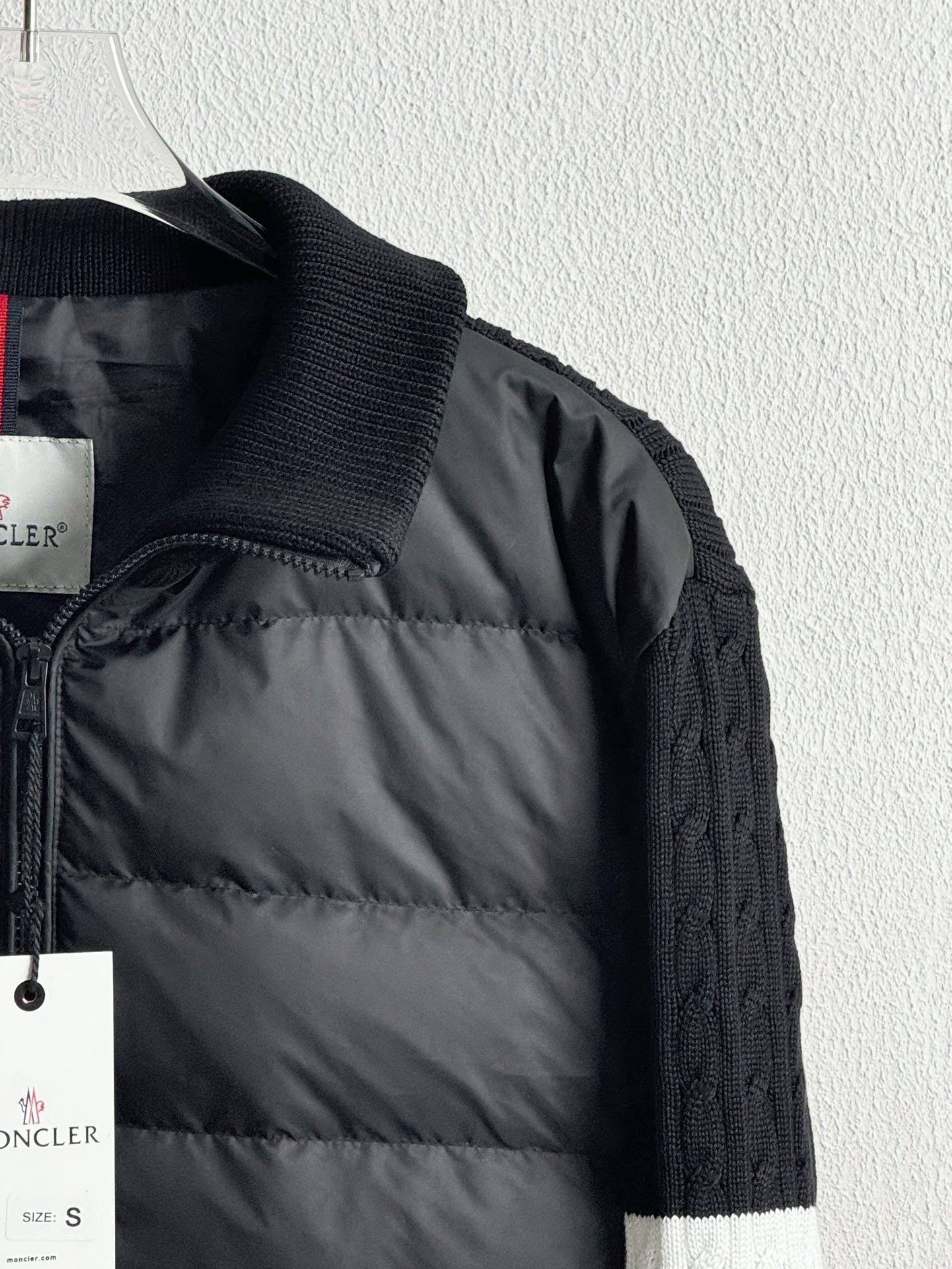 Dark quilted puffer jacket close-up with front quilting, zipper, and hanging tags