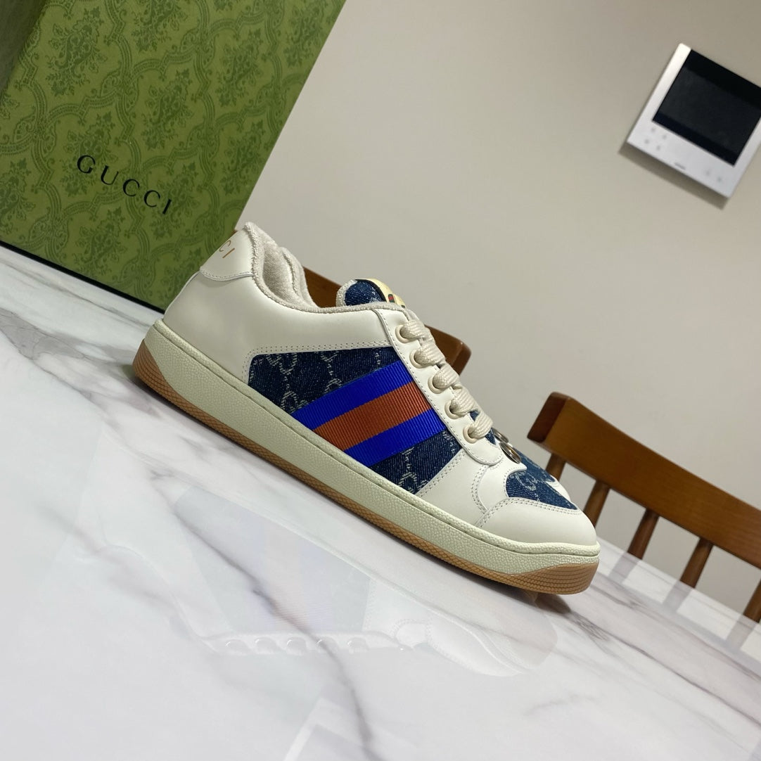 Gucci unisex low-top sneakers angled side view, white upper with blue panel and rainbow web stripe