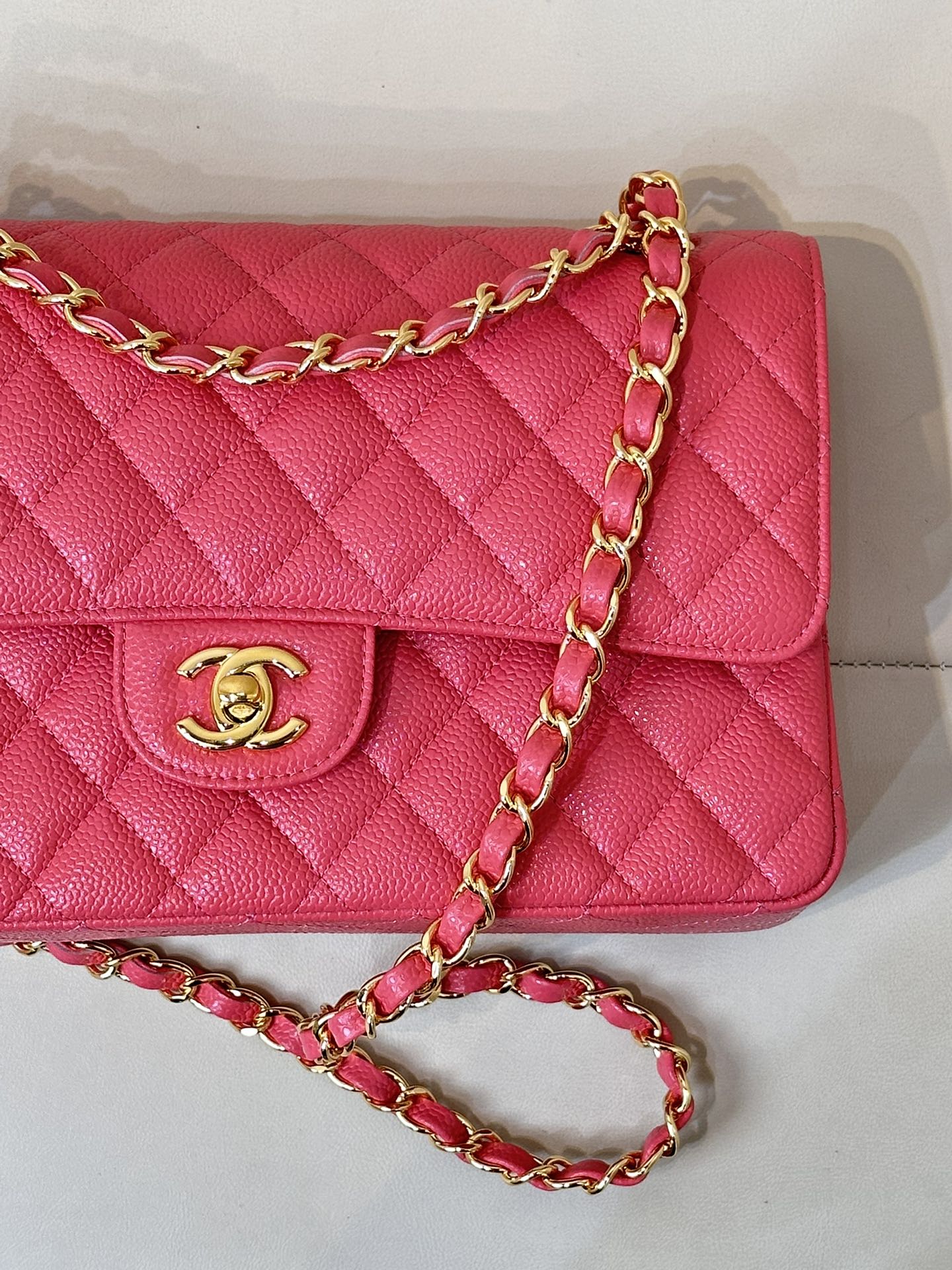 Fuchsia quilted leather flap shoulder bag close-up of gold Chanel logo and chain