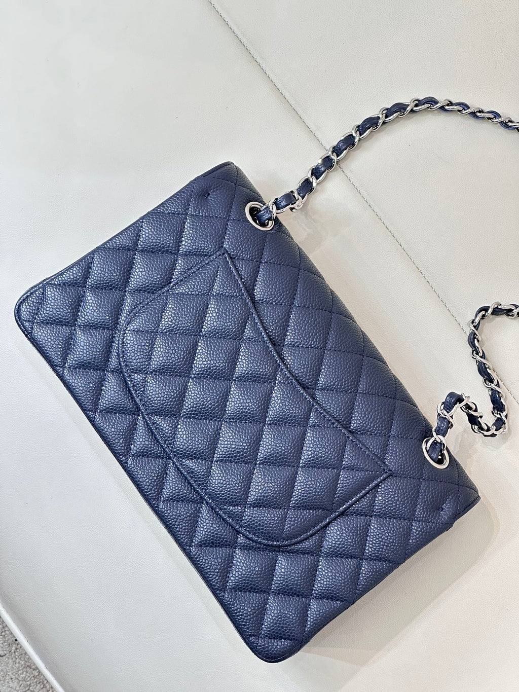 Quilted leather flap shoulder bag with chain strap, angled top view, dark navy blue.