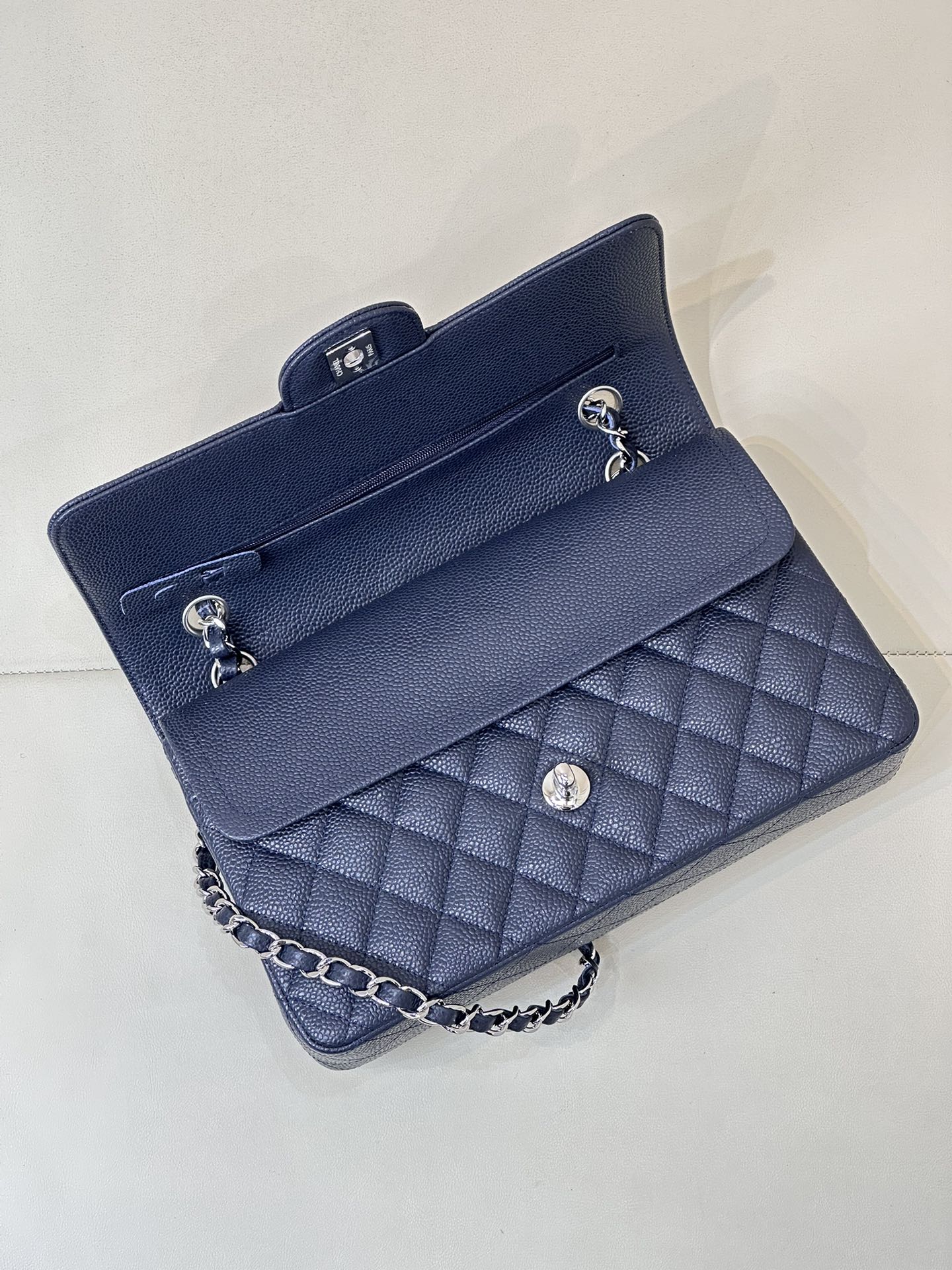 Quilted leather flap shoulder bag with chain strap, front view showing flap interior.