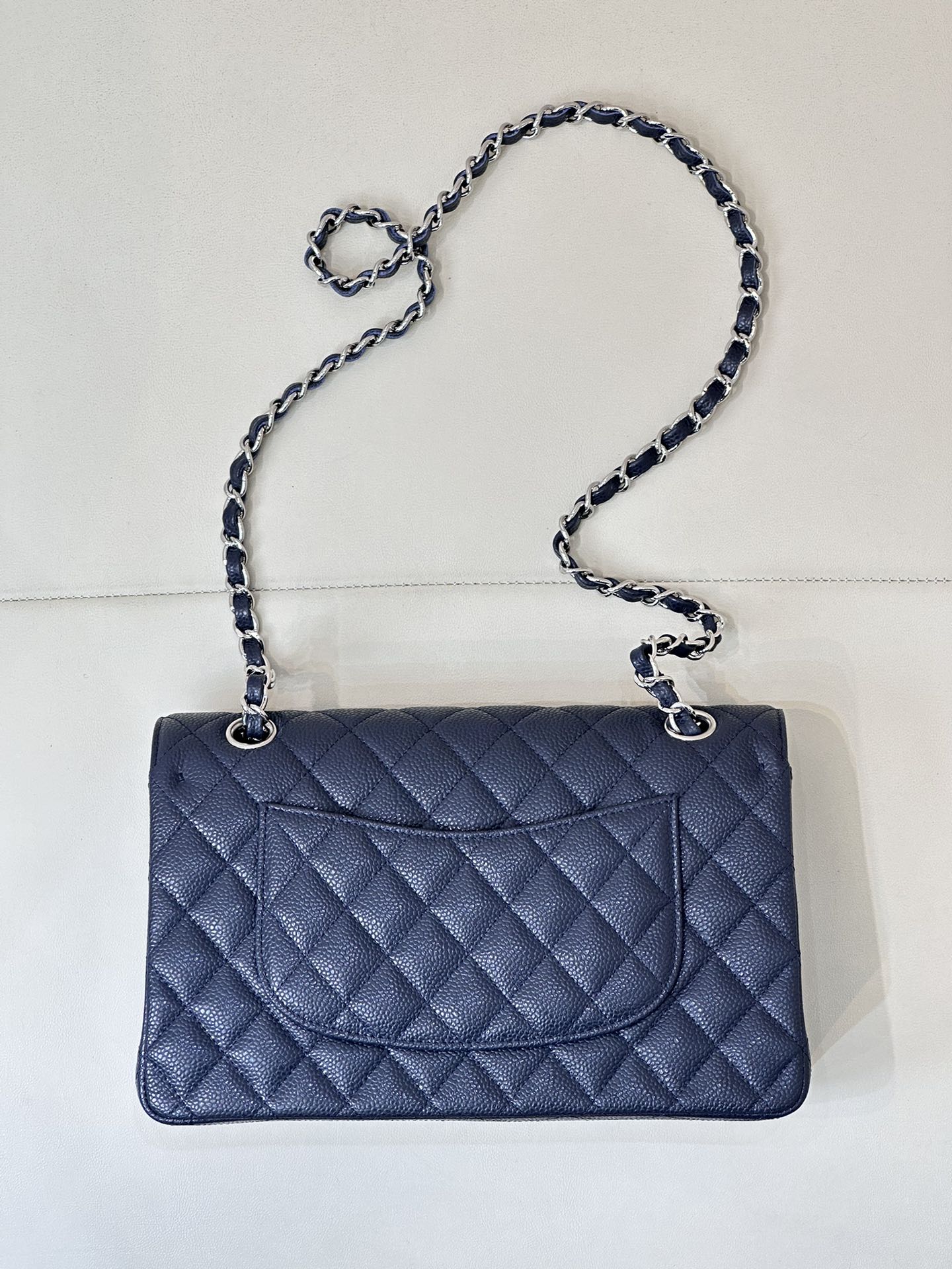 Quilted leather flap shoulder bag with chain strap, straight-on view, dark navy blue.