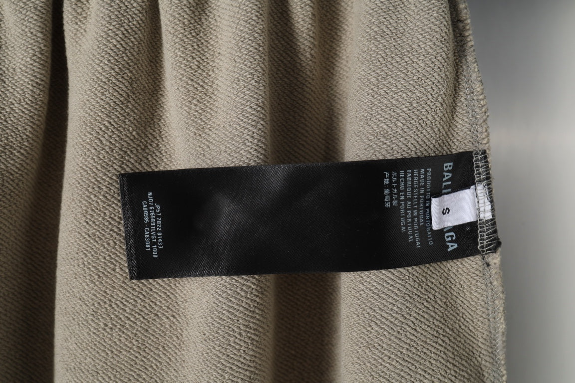 Beige pants fabric with black Balenciaga care label near hem.