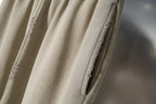 Beige pants with side seam detail and small distressed patches on fabric.