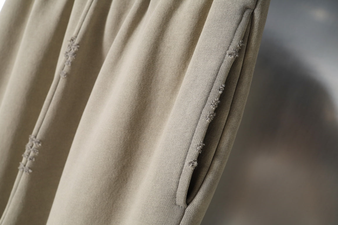 Beige pants with distressed seams along the leg