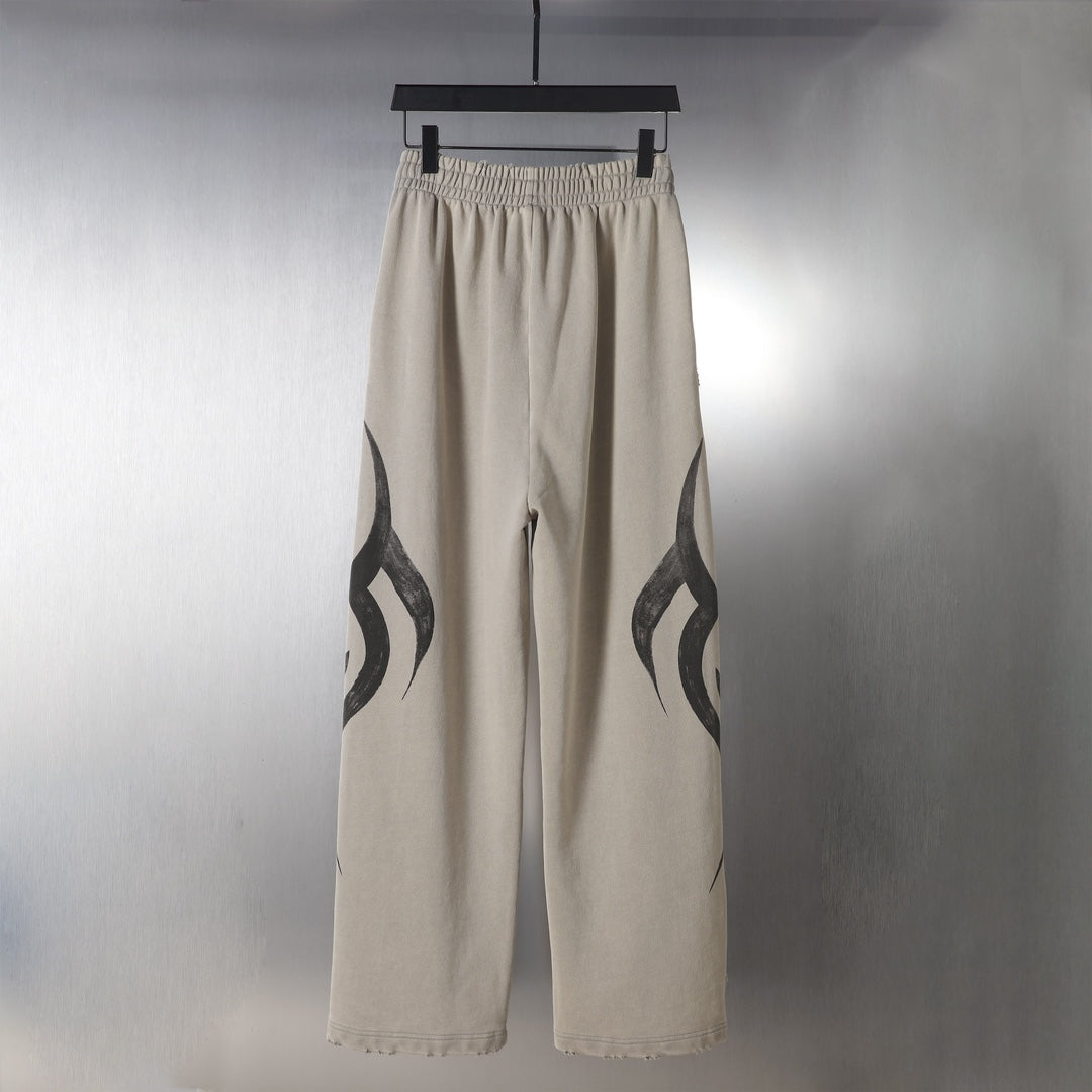 Beige drawstring pants with black flame graphic along the sides.
