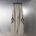 Beige wide-leg pants with black flame graphic detail on the outer legs