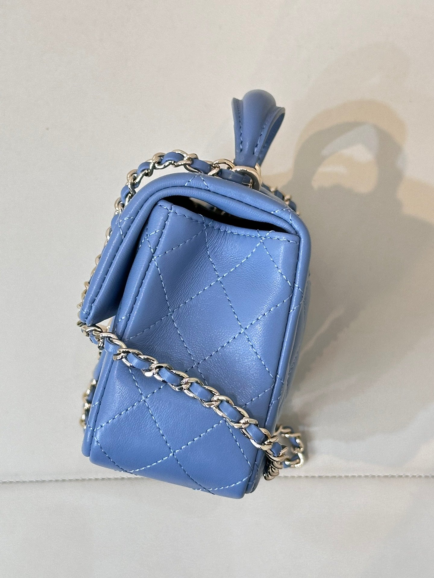 Chanel blue quilted mini handbag with top handle, flap, and chain crossbody strap