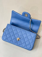 Chanel blue quilted flap bag with gold logo button and chain strap, side view
