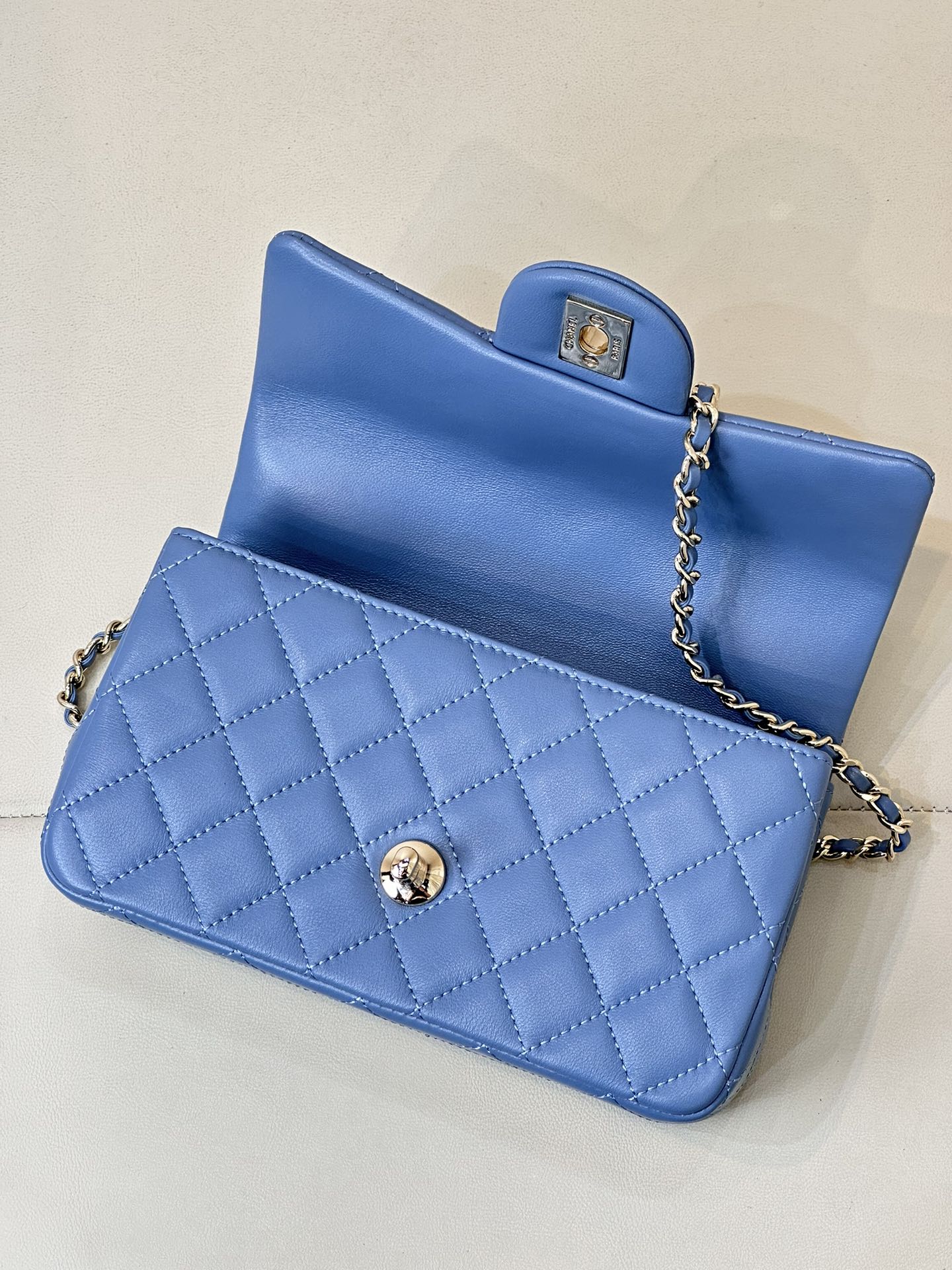 Chanel blue quilted flap bag with gold logo button and chain strap, side view