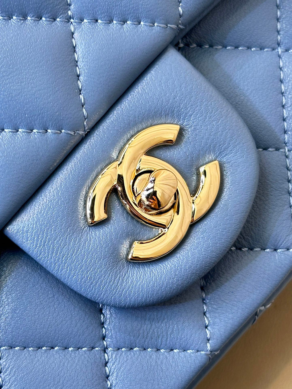 Chanel blue quilted bag detail with gold CC logo medallion on front flap