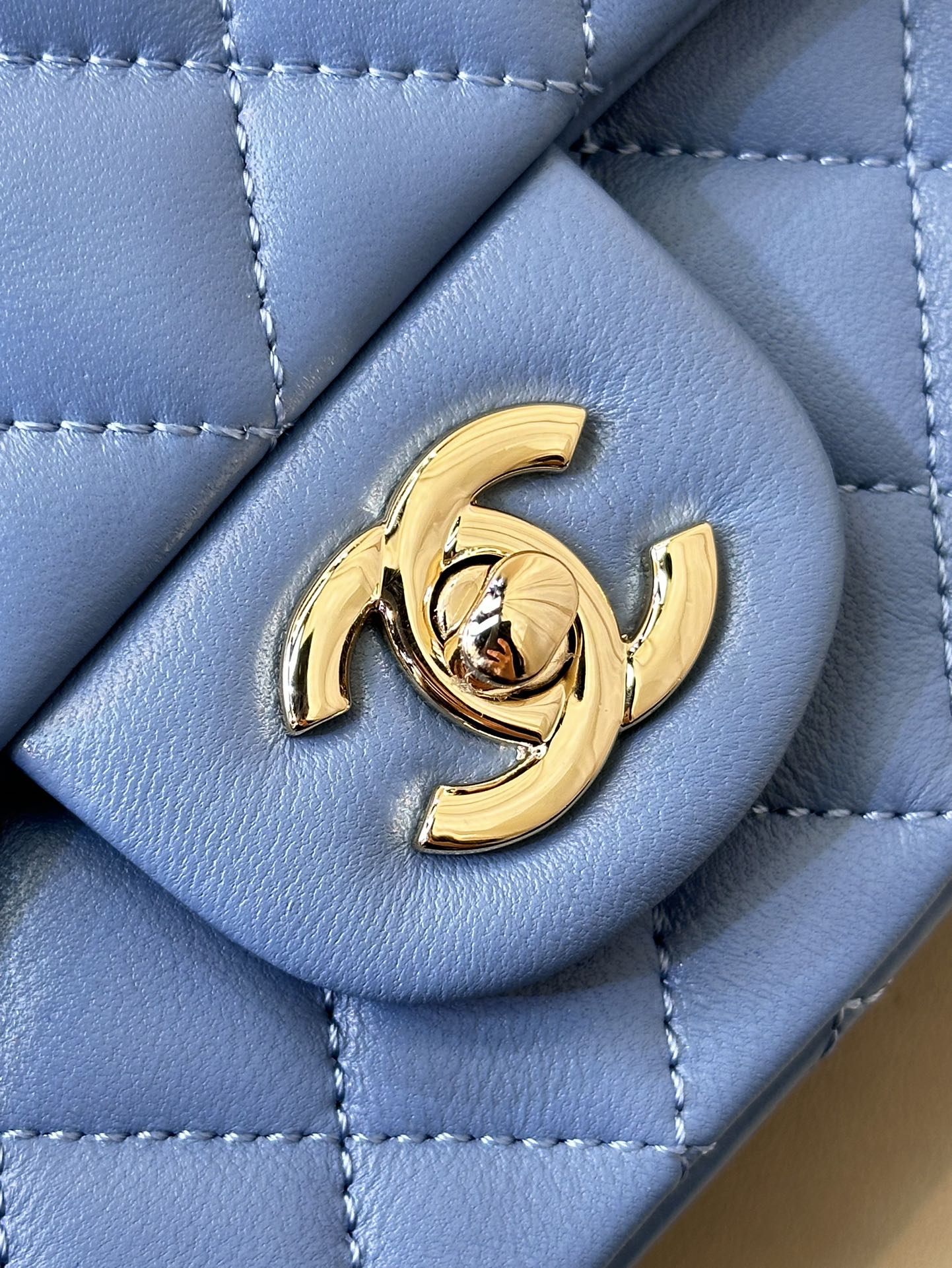 Chanel blue quilted bag detail with gold CC logo medallion on front flap