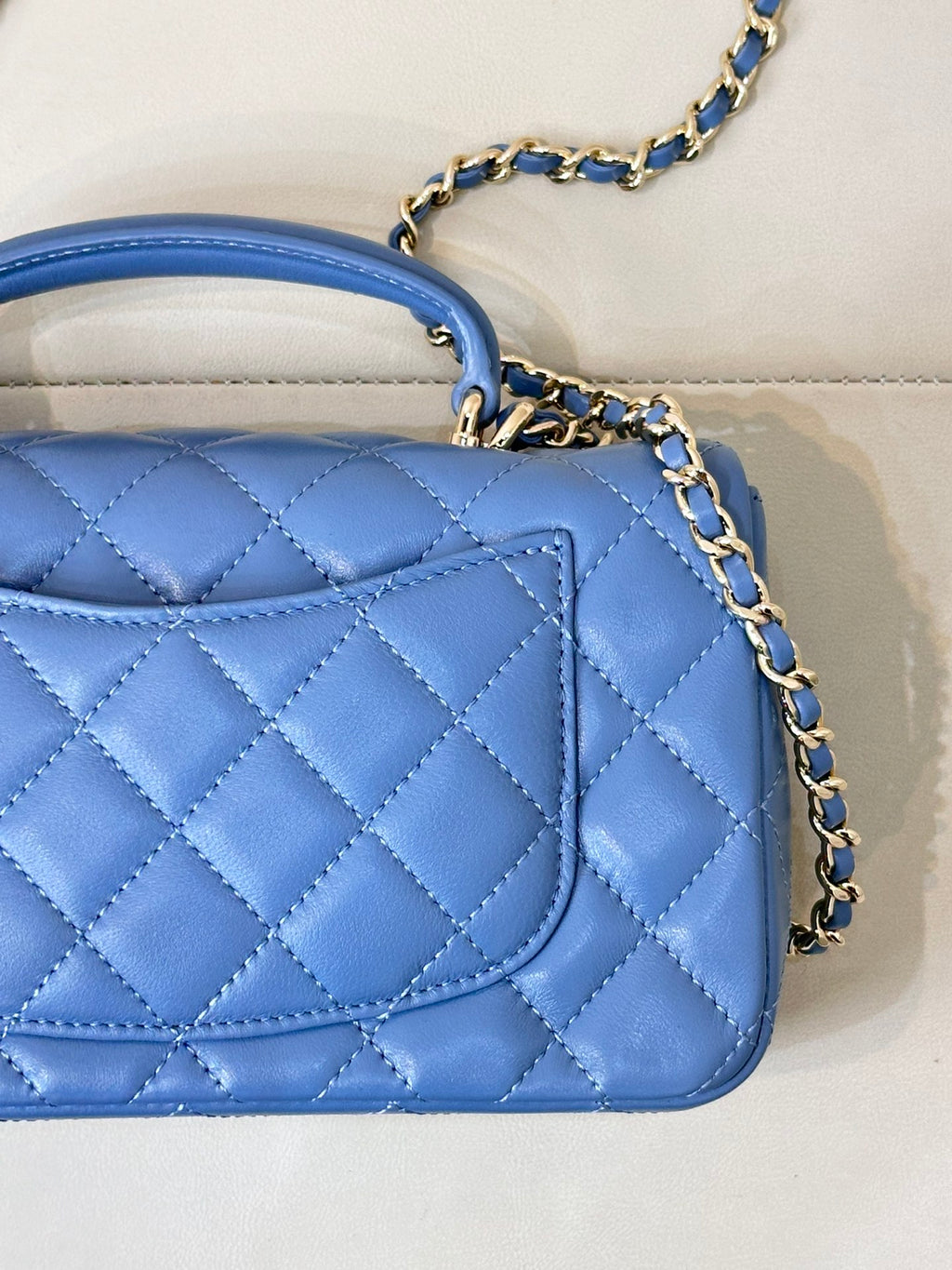 Chanel blue quilted handbag showing front flap and chain strap with gold logo