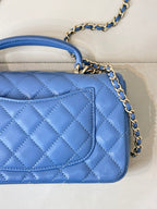 Chanel blue quilted handbag showing front flap and chain strap with gold logo