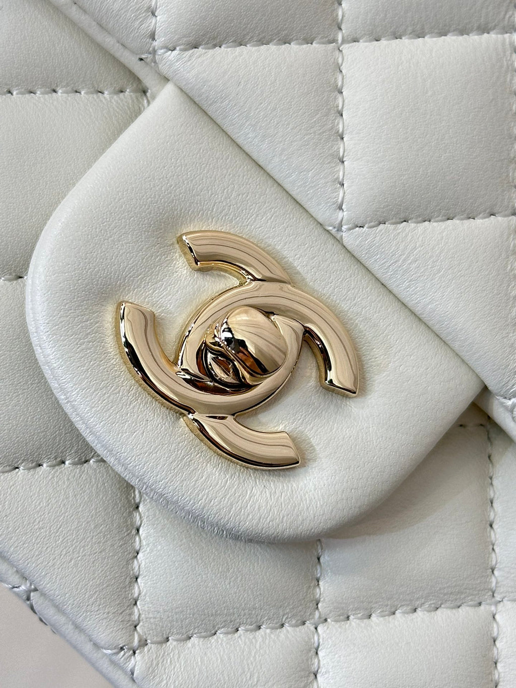 Chanel white quilted handbag close-up of gold-tone logo turn-lock hardware