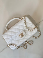 Chanel white quilted mini handbag with top handle, chain strap, and turn-lock logo