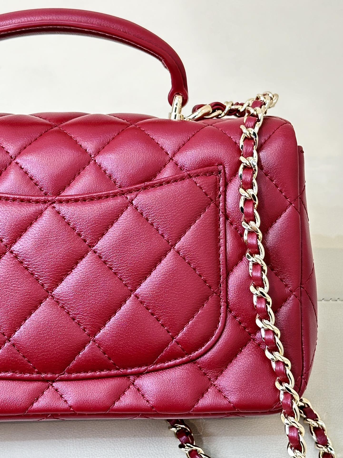 Chanel quilted flap bag close-up, maroon-pink leather with chain and stitched panel