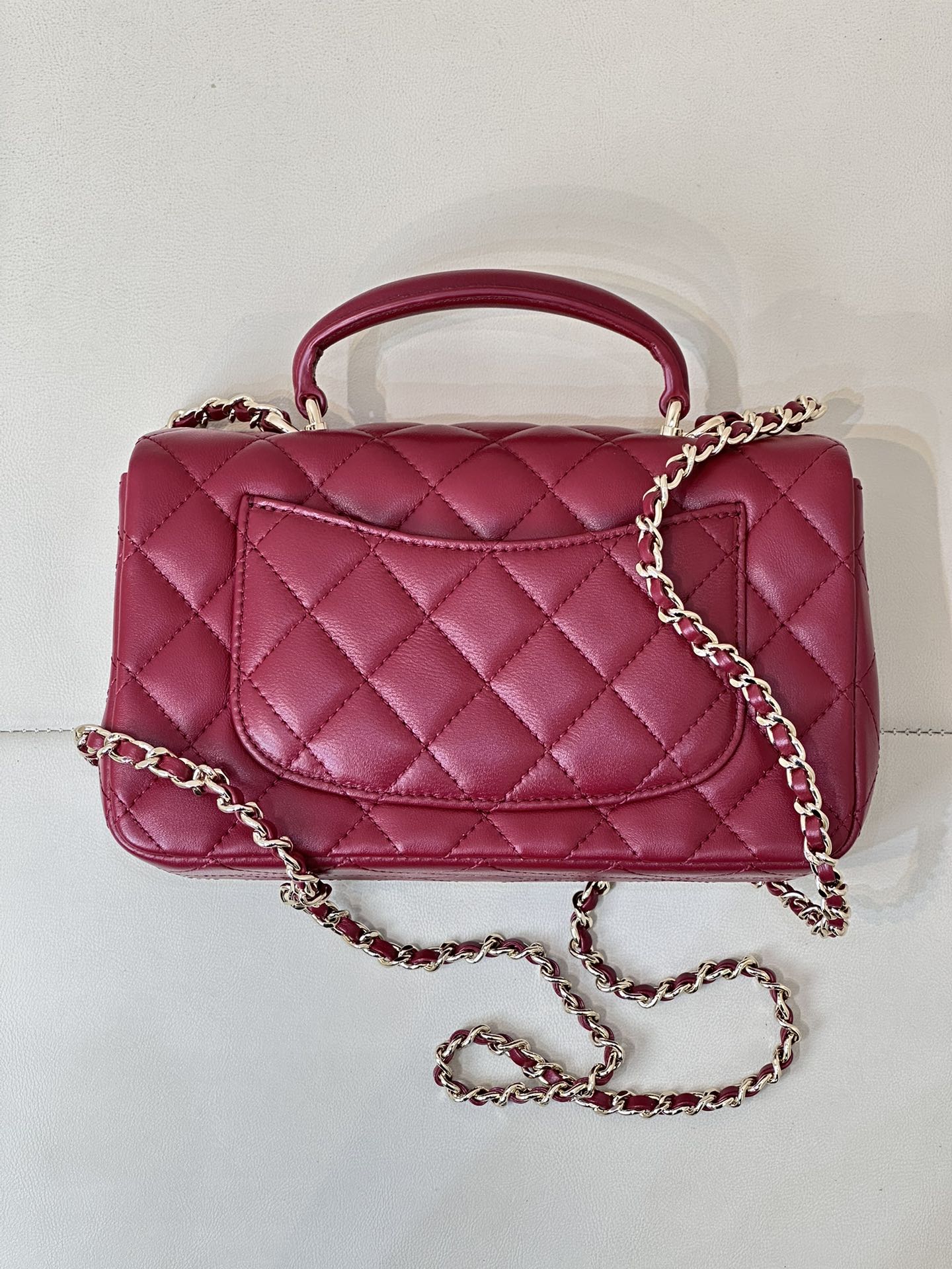 Chanel quilted flap bag back view, maroon-pink leather with chain strap