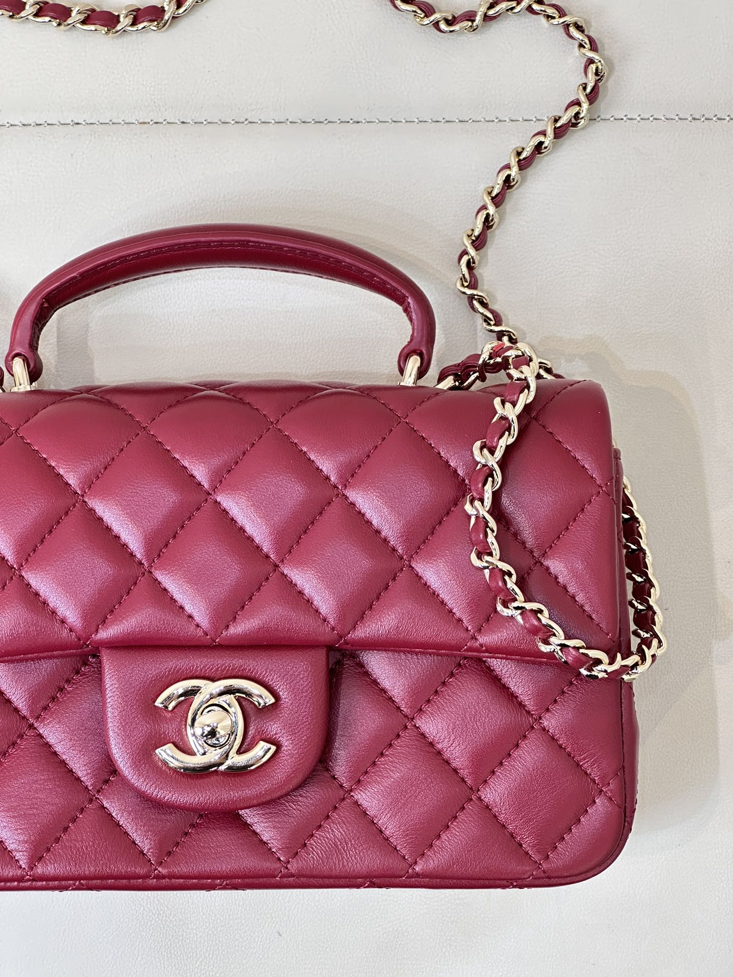 Chanel quilted flap bag close-up, maroon-pink leather with CC logo and chain